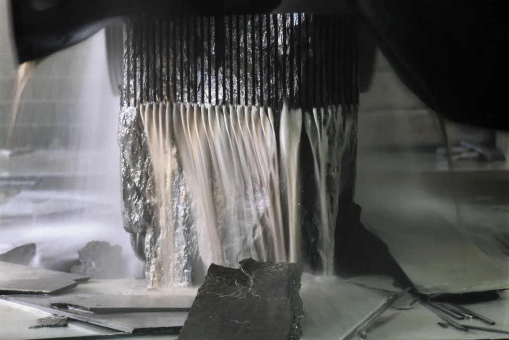 Valser Quarzit wird auf der Gattersäge in Platten zersägt, mit Kühlwasser