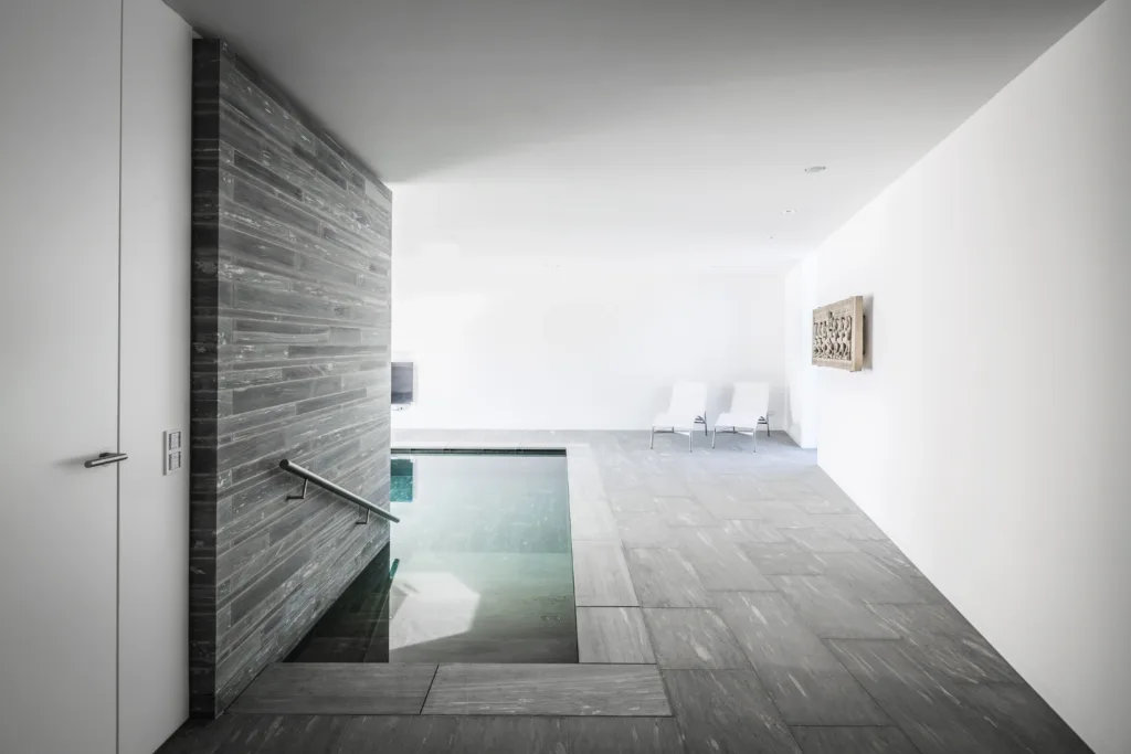 Gesägtes Schichtmauerwerk und grobgeschliffene Bodenplatten aus Valser Quarzit für Pool im Privathaus in Köln