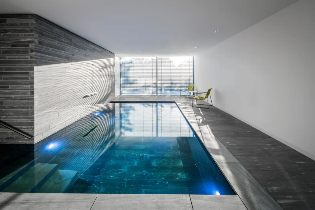 Pool mit gesägtem Schichtmauerwerk und grobgeschliffenen Bodenplatten aus Valser Quarzit im Privathaus in Köln